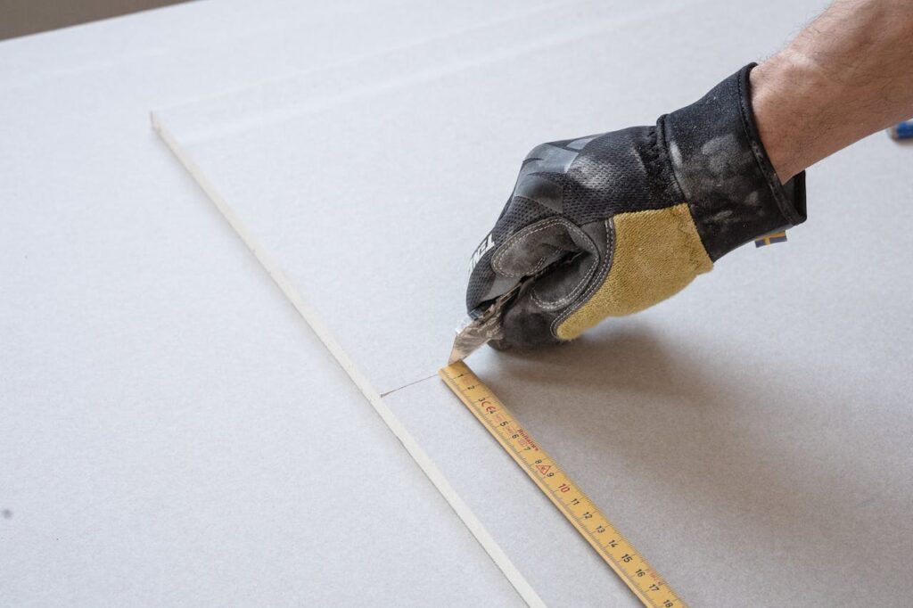 Worker cutting drywall panel for professional interior wall installation