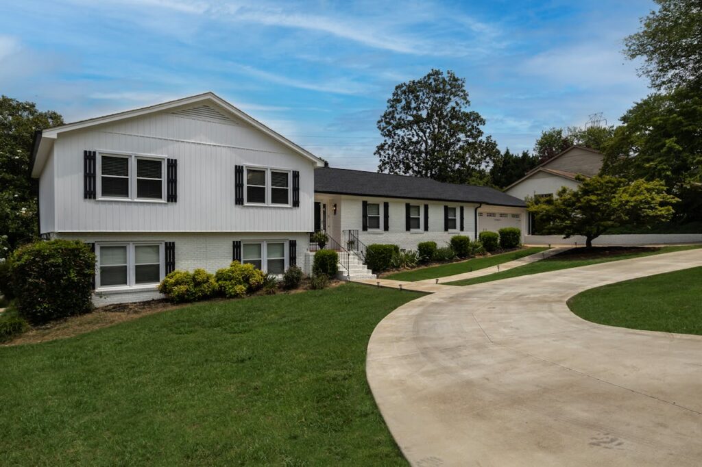 White painted house exterior with black shutters and landscaped front yard